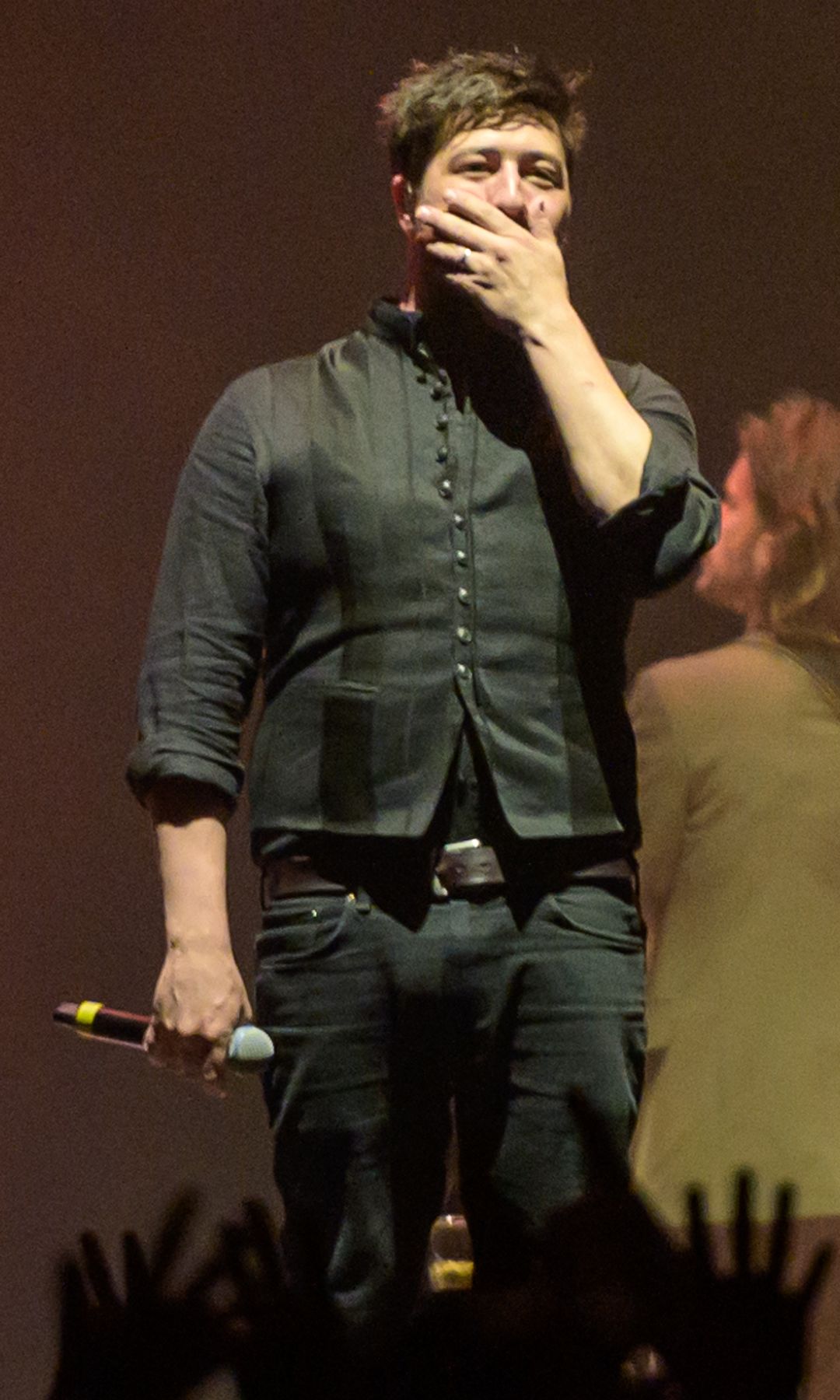 Marcus Mumford se produit sur scène dans une chemise boutonnée noire