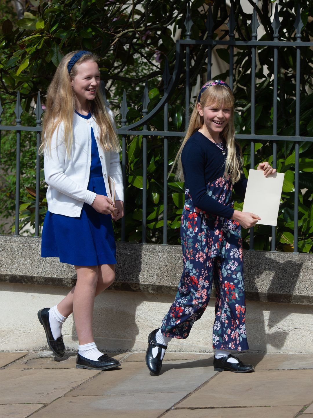 Savannah Phillips in a white coat and blue dress with Isla Phillips in floral trousers and blue cardigan