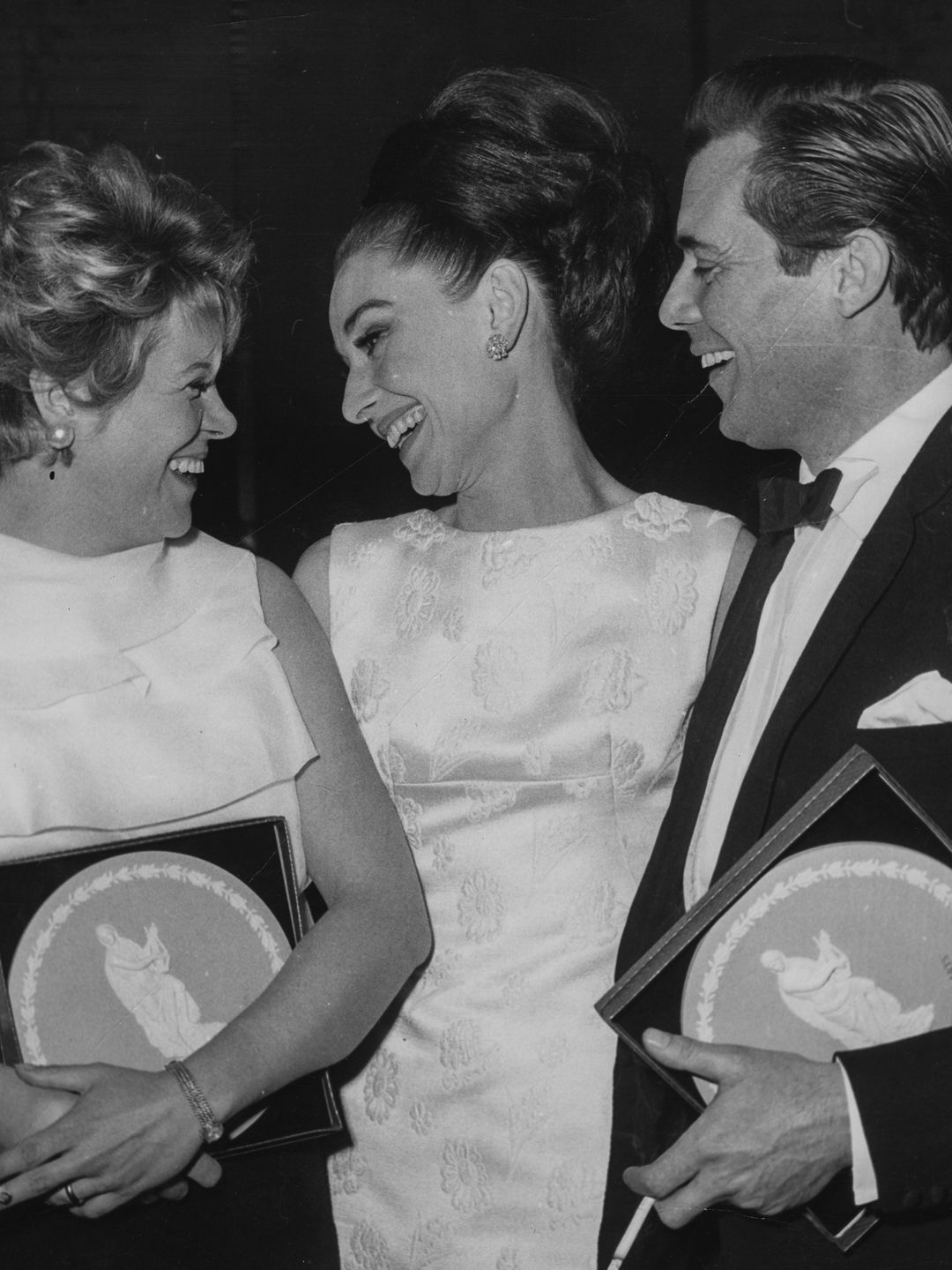 Audrey Hepburn smiling with Rachel Roberts and Dirk Bogarde at the BAFTAs 