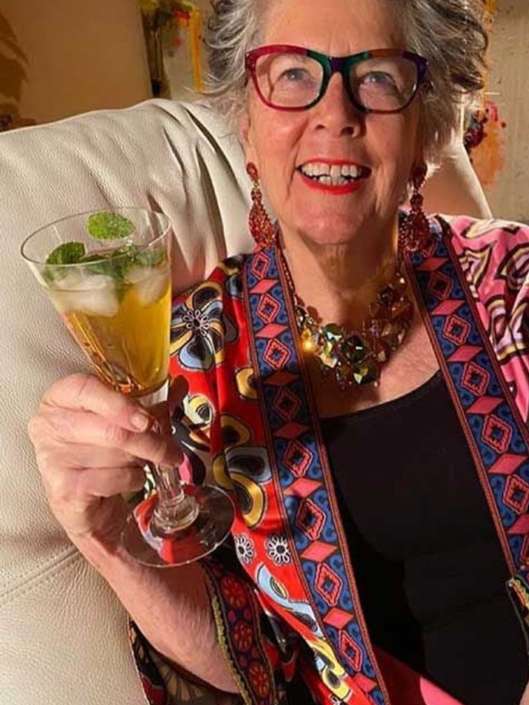 Prue Leith in an armchair with a glass of alcohol