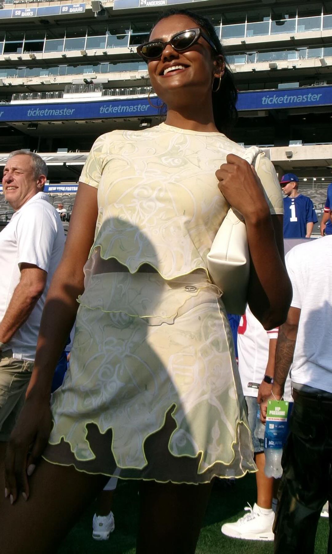 Simone Ashley poses in a mini skirt and crop top at a NFL game