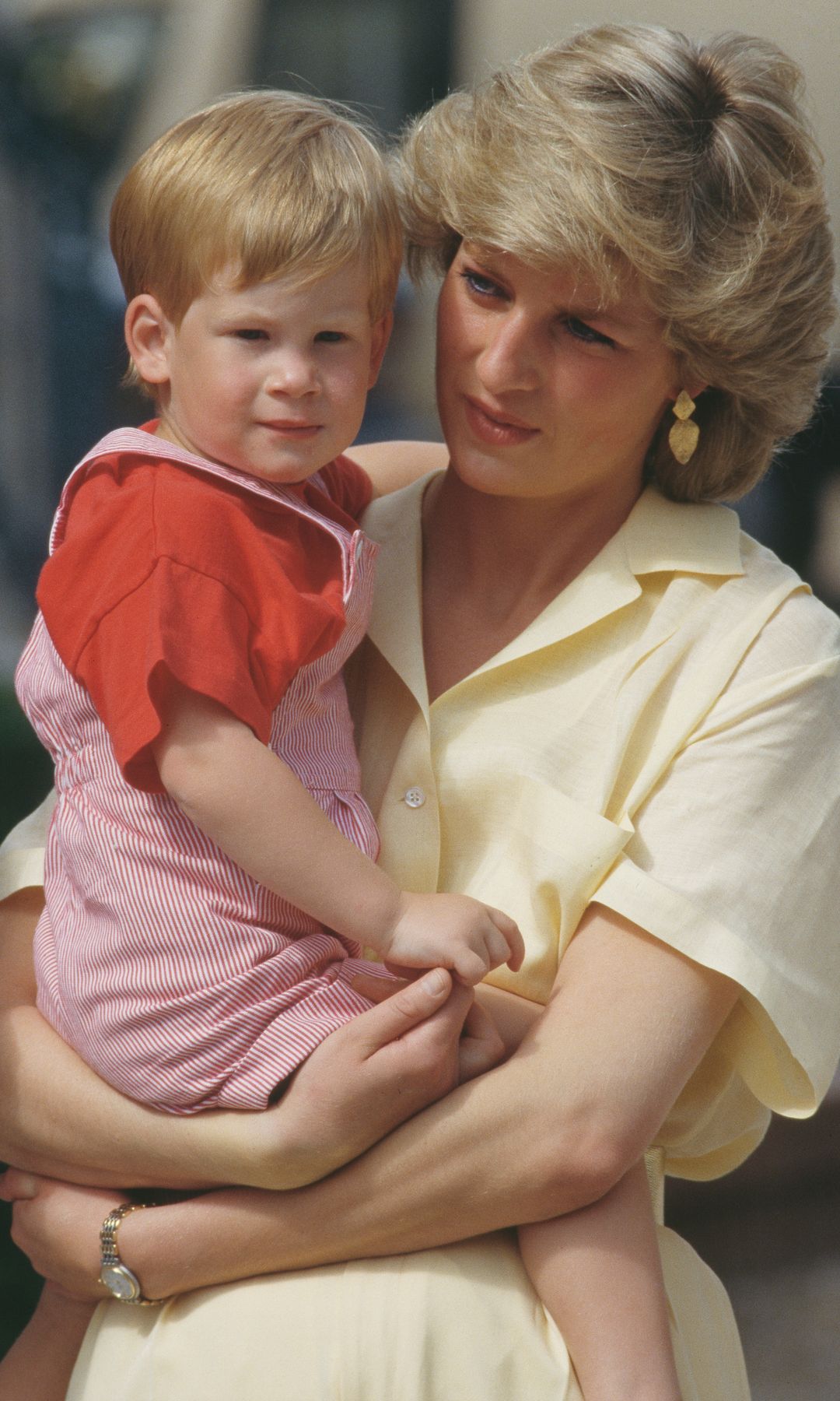 Princess Diana holding her son Prince Harry who wore red dungarees