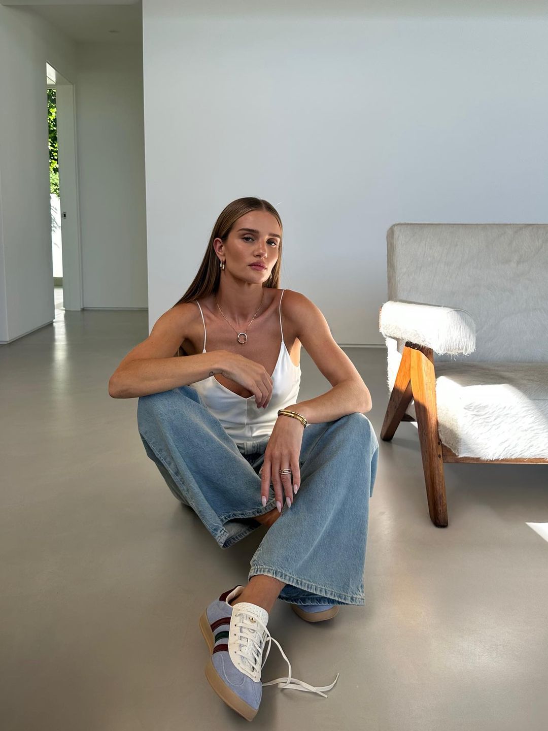 Rosie Huntington Whiteley poses for a Instagram photo in blue jeans, a white cami and blue sneakers
