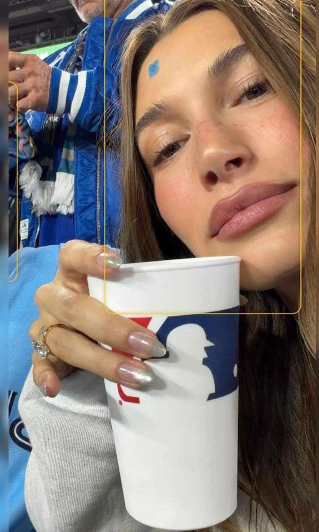 hailey bieber holding a cup showing off her silver nails 