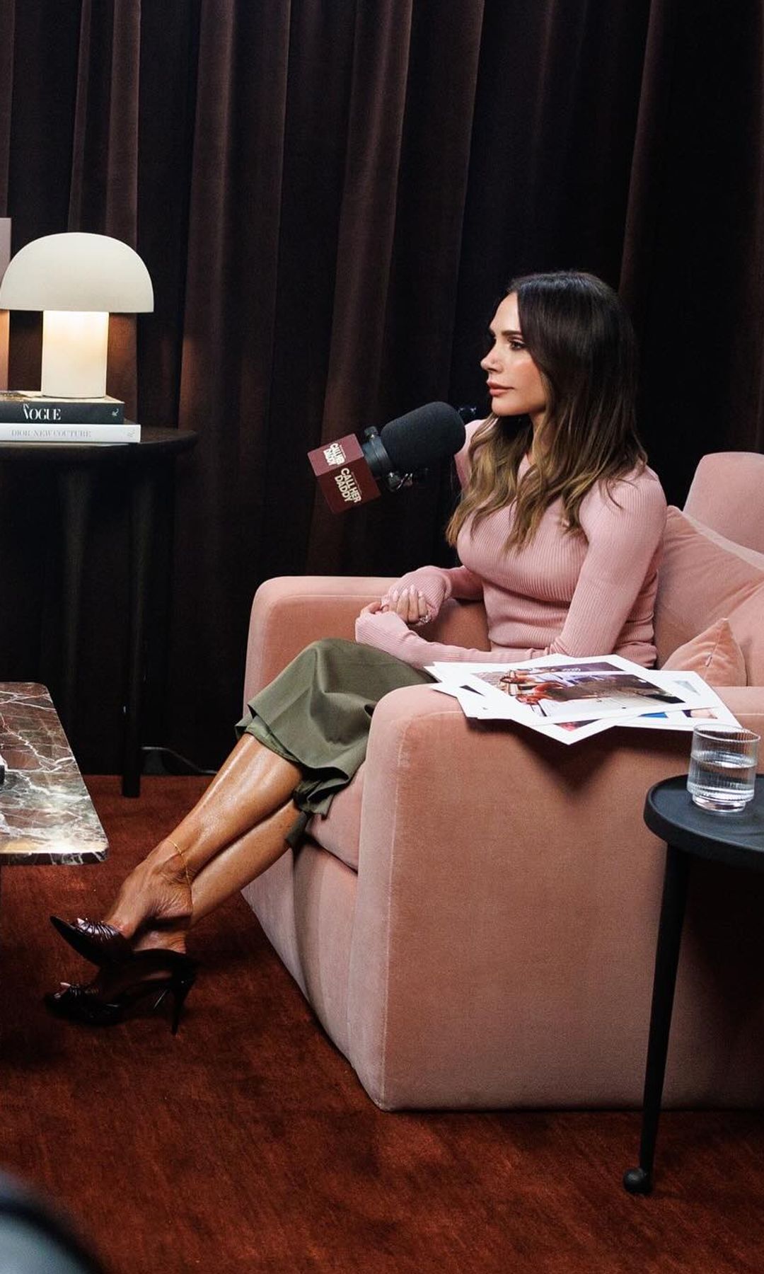 Victoria Beckham sits on a pink sofa to record Call Her Daddy the podcast