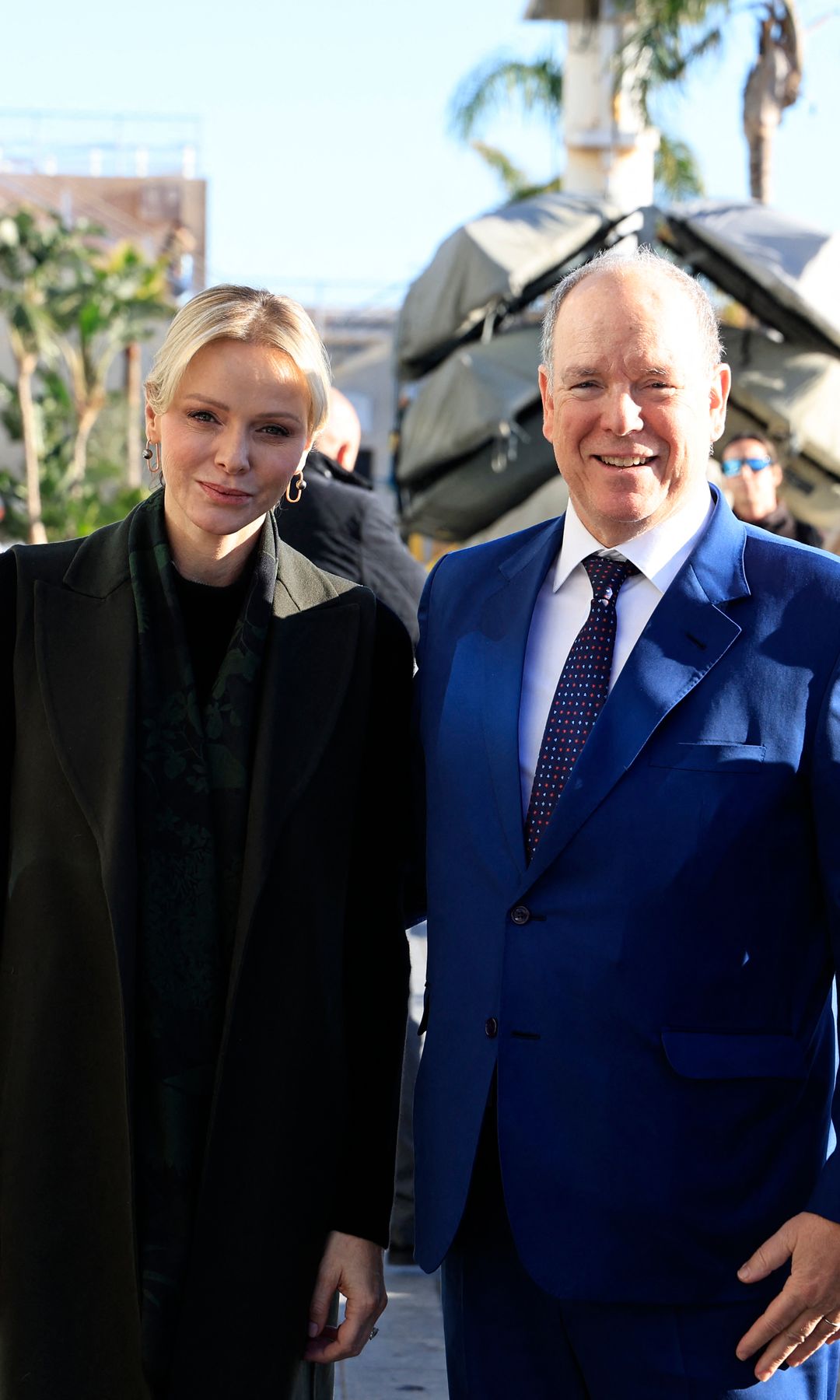 Princess Charlene in a black coat and Prince Albert in a blue suit