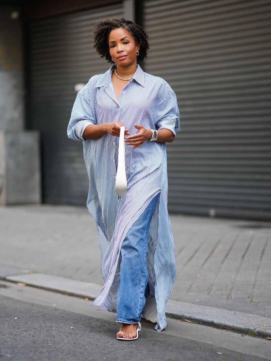 Ellie Delphine wears a white long maxi shirt dress with stripes from The Frankie Shop teamed with a white bag from The Row.