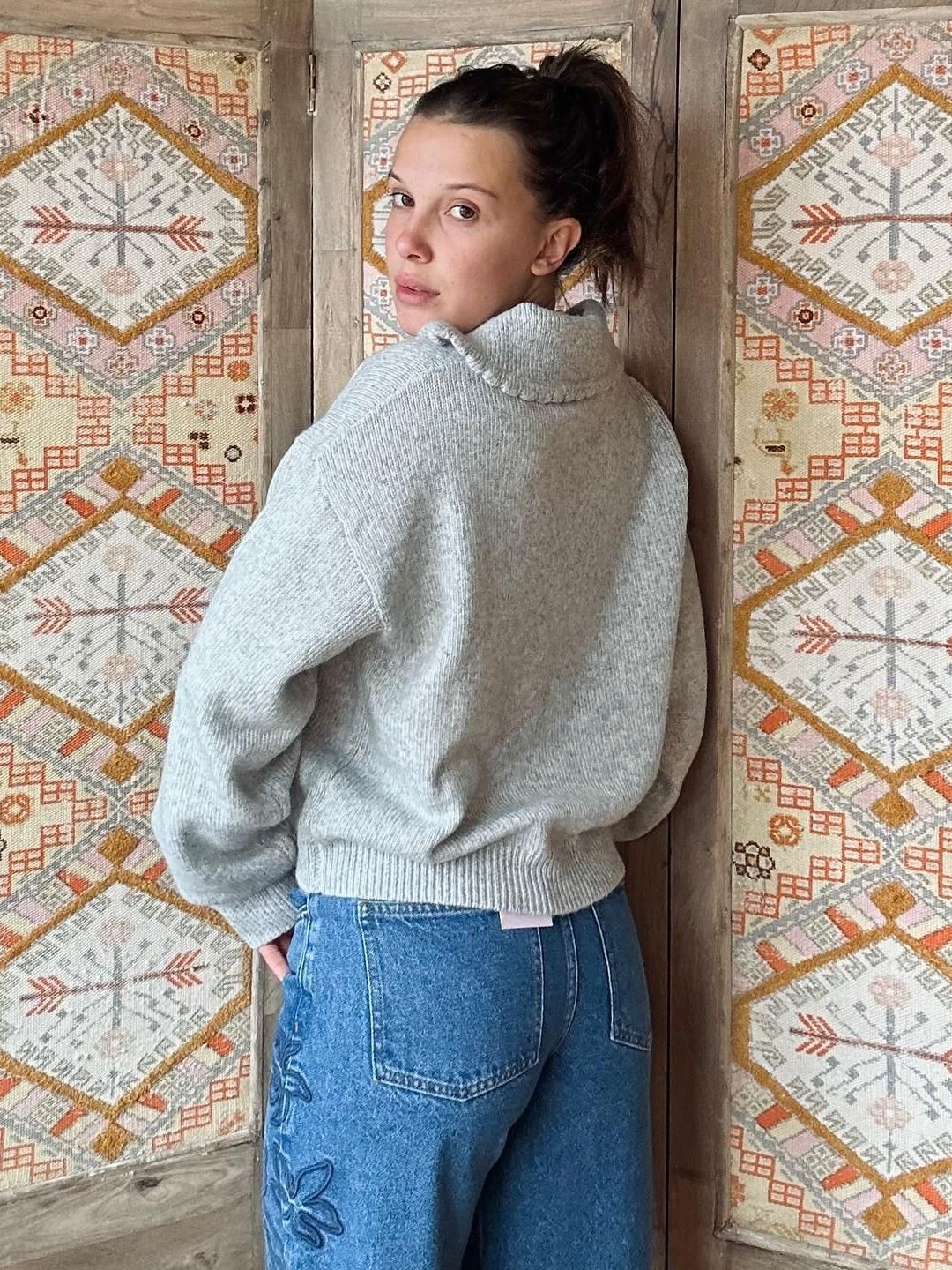 Millie Bobby Brown poses in a grey knit and jeans 