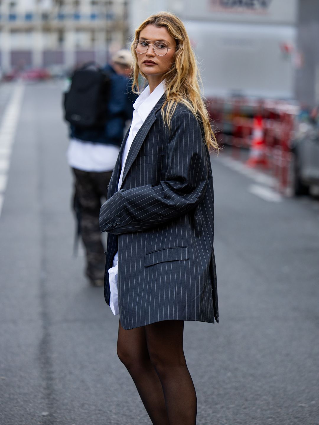 Chloe Lecareux wears black striped oversized blazer, white button shirt dress, tights, white bag outside Viktor&Rolf during the Haute Couture Spring/Summer 2024