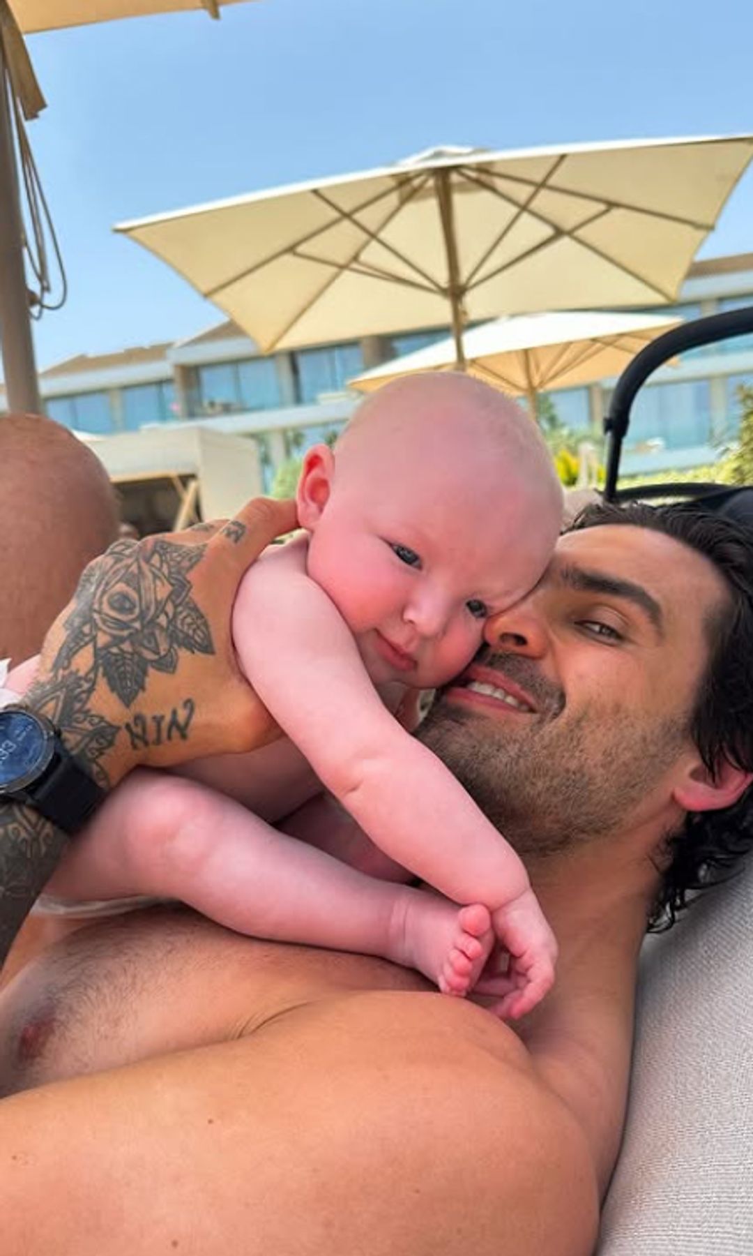 Adam Collard snuggled up with a baby underneath umbrellas