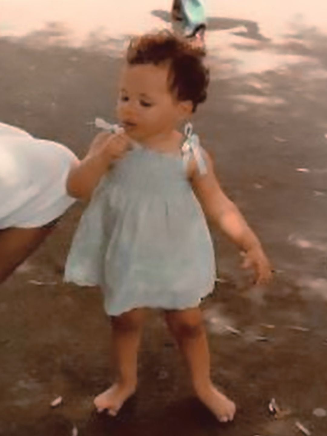 A baby Meghan Markle in a blue dress blowing bubbles