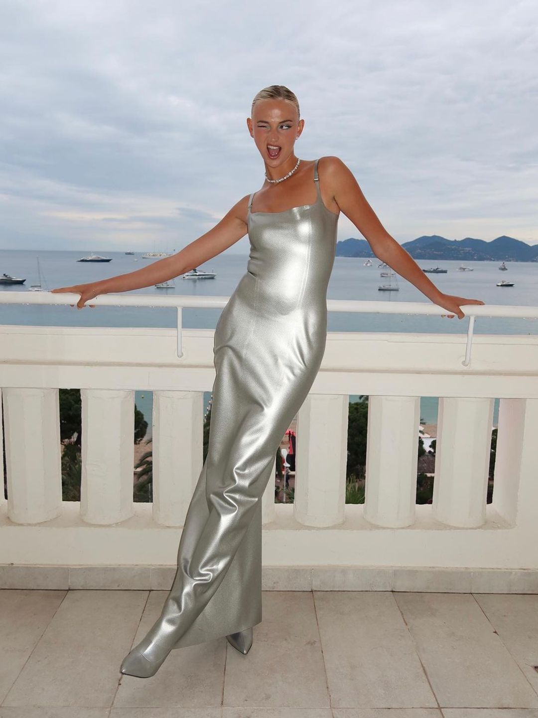 Mia Regan wears a latex silver dress and boots to Cannes Film Festival
