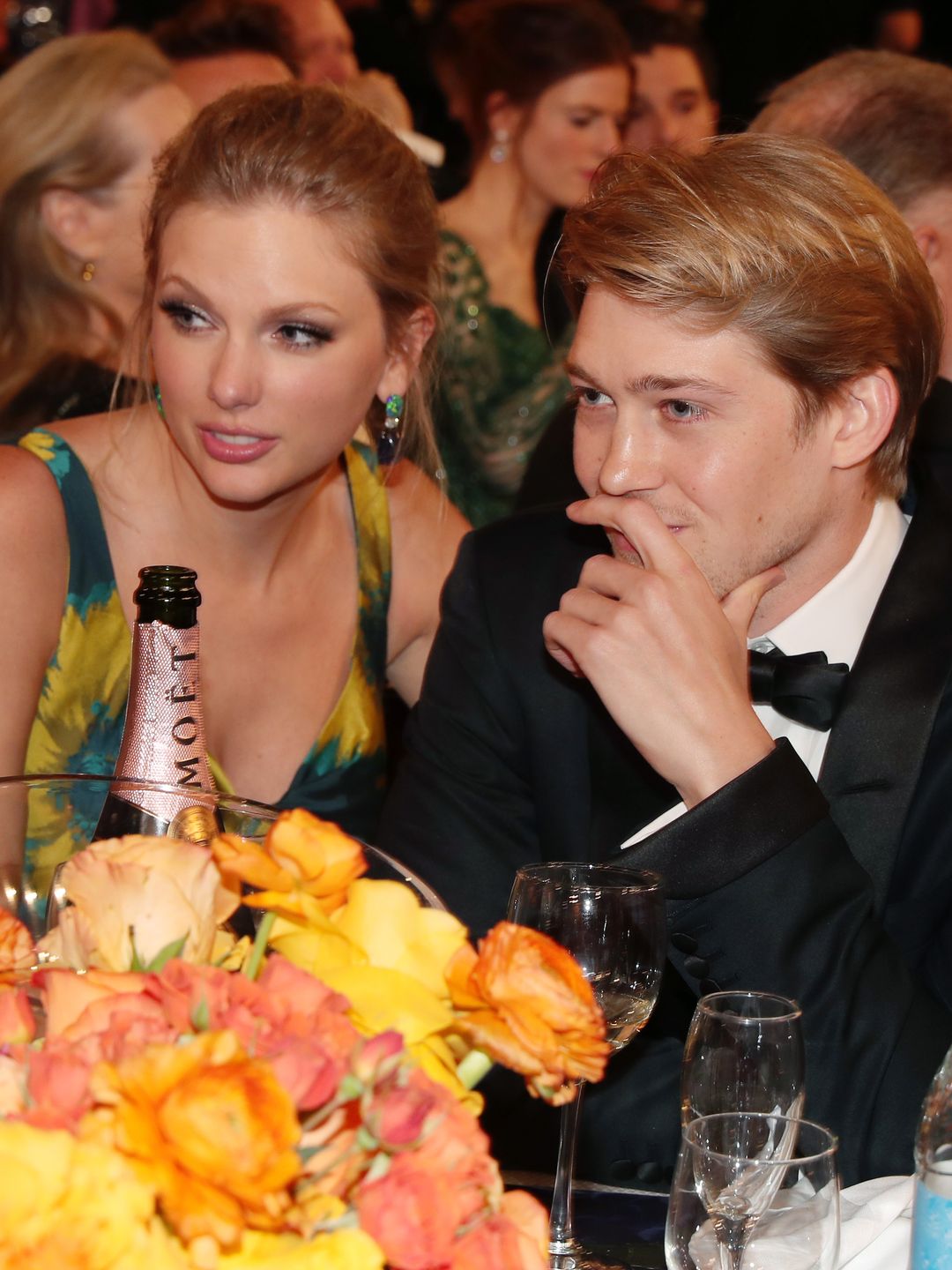 Taylor and Joe at an awards ceremony, sat looking over to the left while leaning into each other