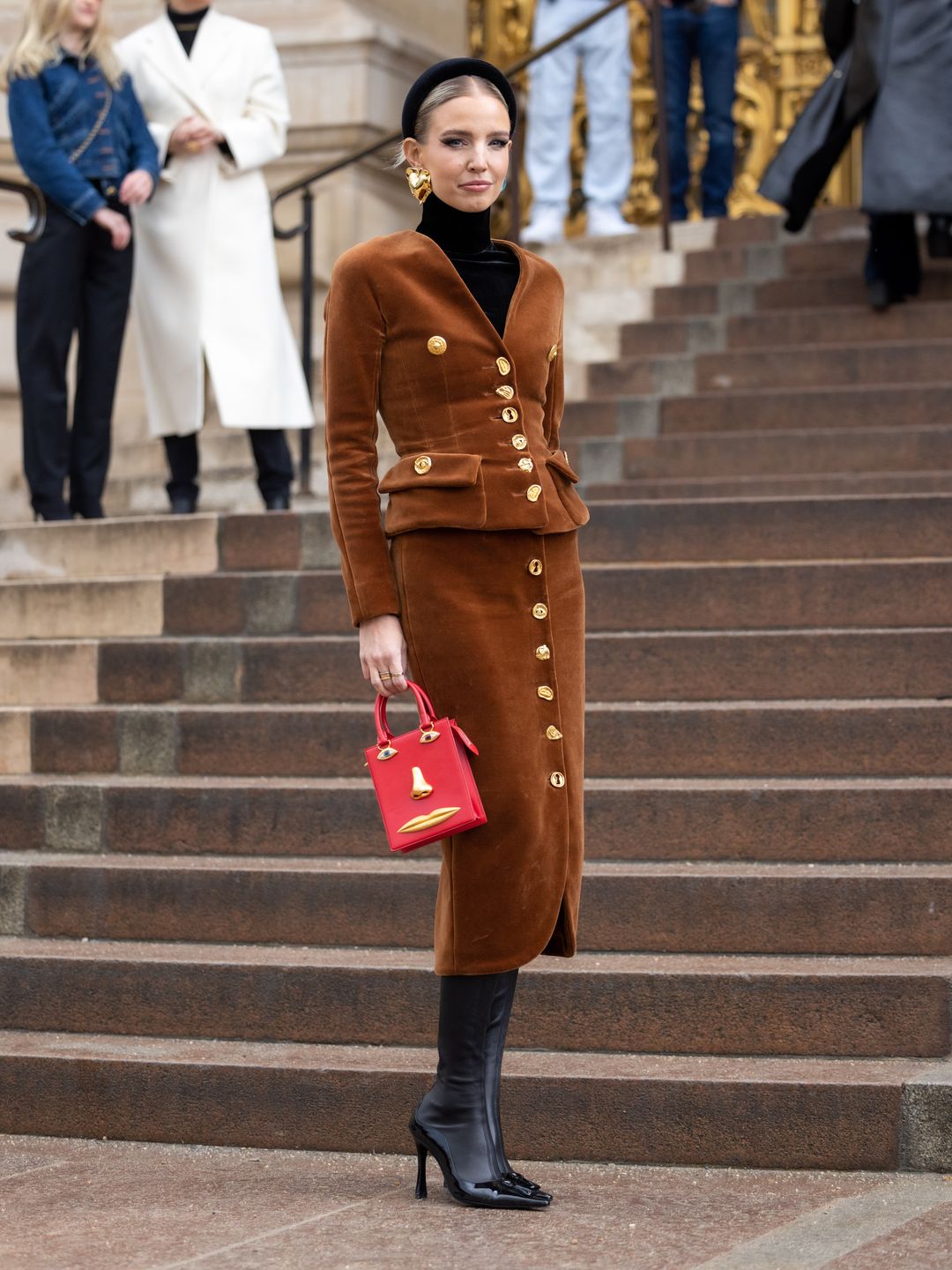 Leonie Hanne attends the Schiaparelli Haute Couture Spring/Summer 2024 show wearing a brown twin piece and red handbag
