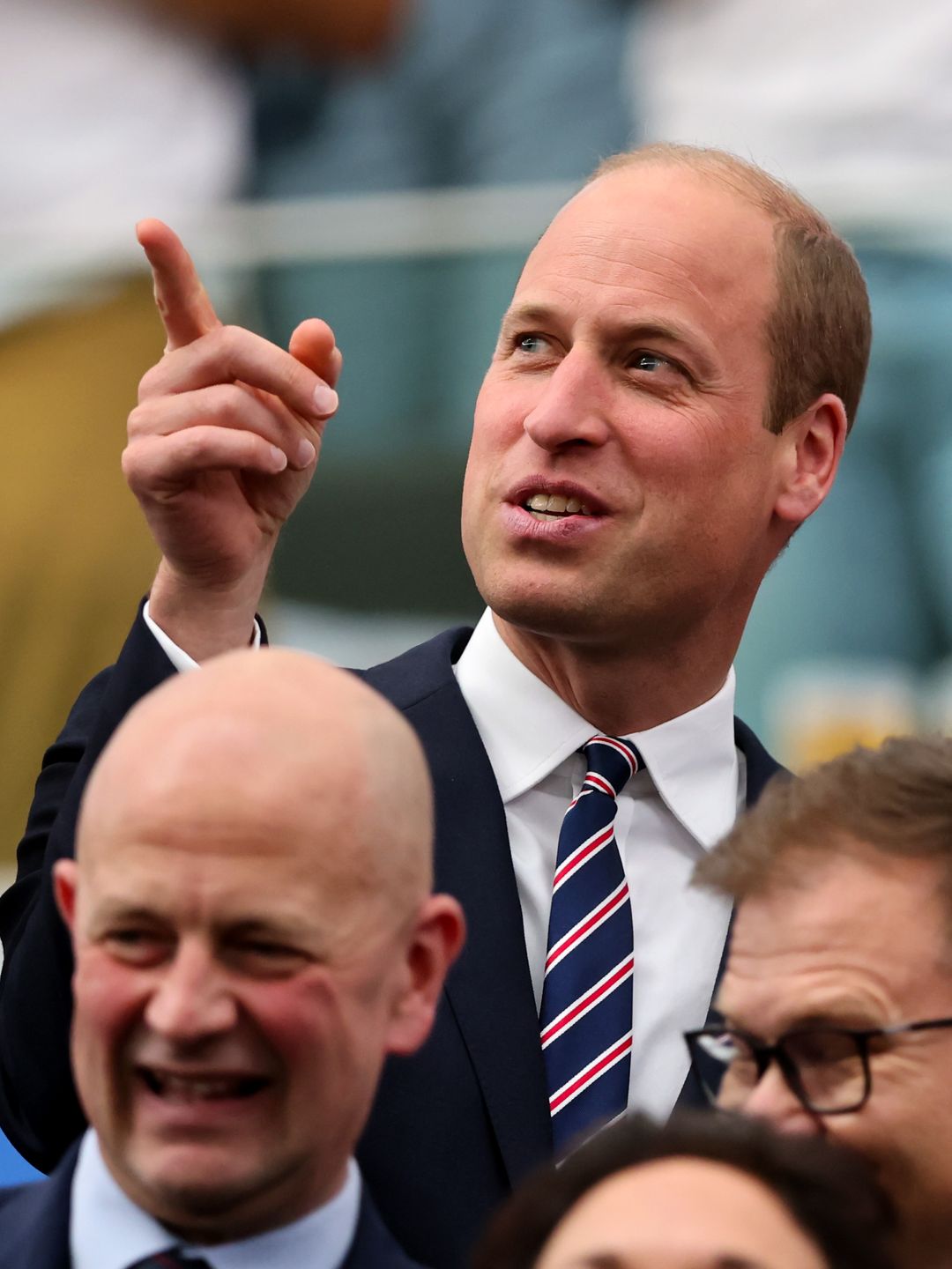 Prince William pointing while alongside King Frederik at football match