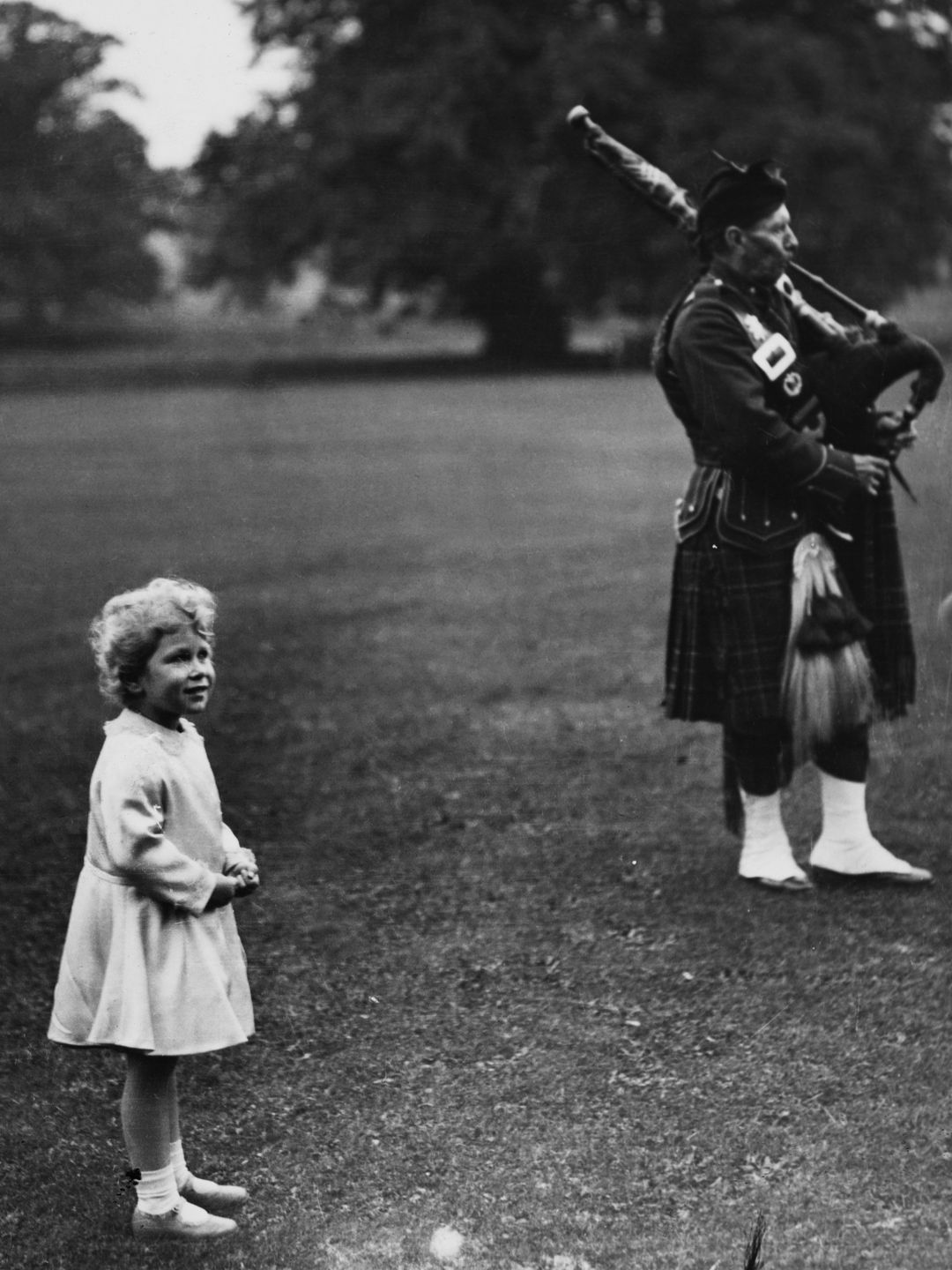 A young Queen Elizabeth next to a bagpipe player