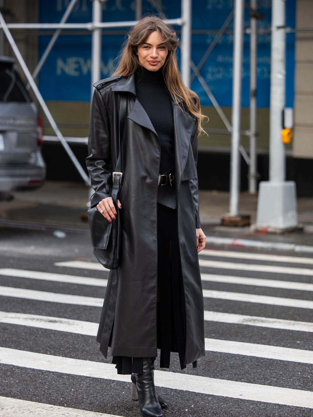 Mara Lafontan wears black coat, turtleneck, skirt with slit, bag, knee high boots outside Michael Kors 
