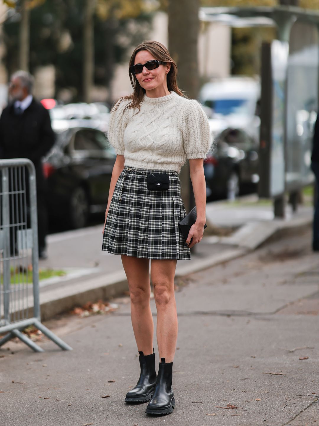 A Fashion Week guest a plaid skirt with a puff-sleeve cable knit sweater 