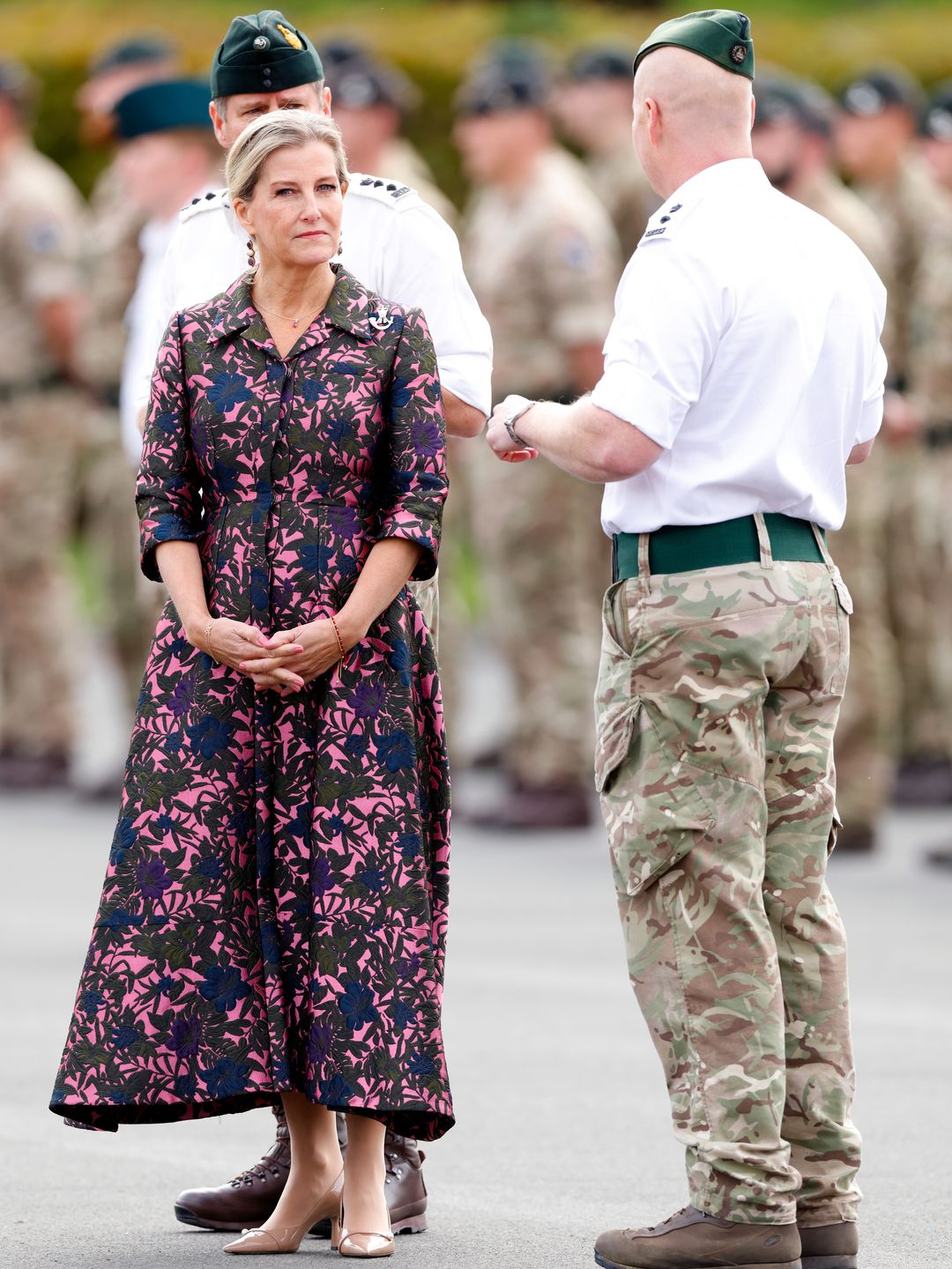 Sophie in floral dress with members of military