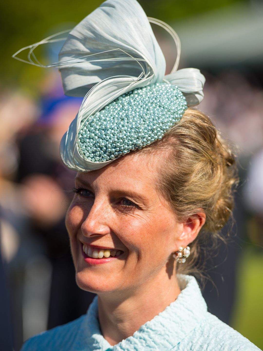 woman wearing turquoise hat with pearls 