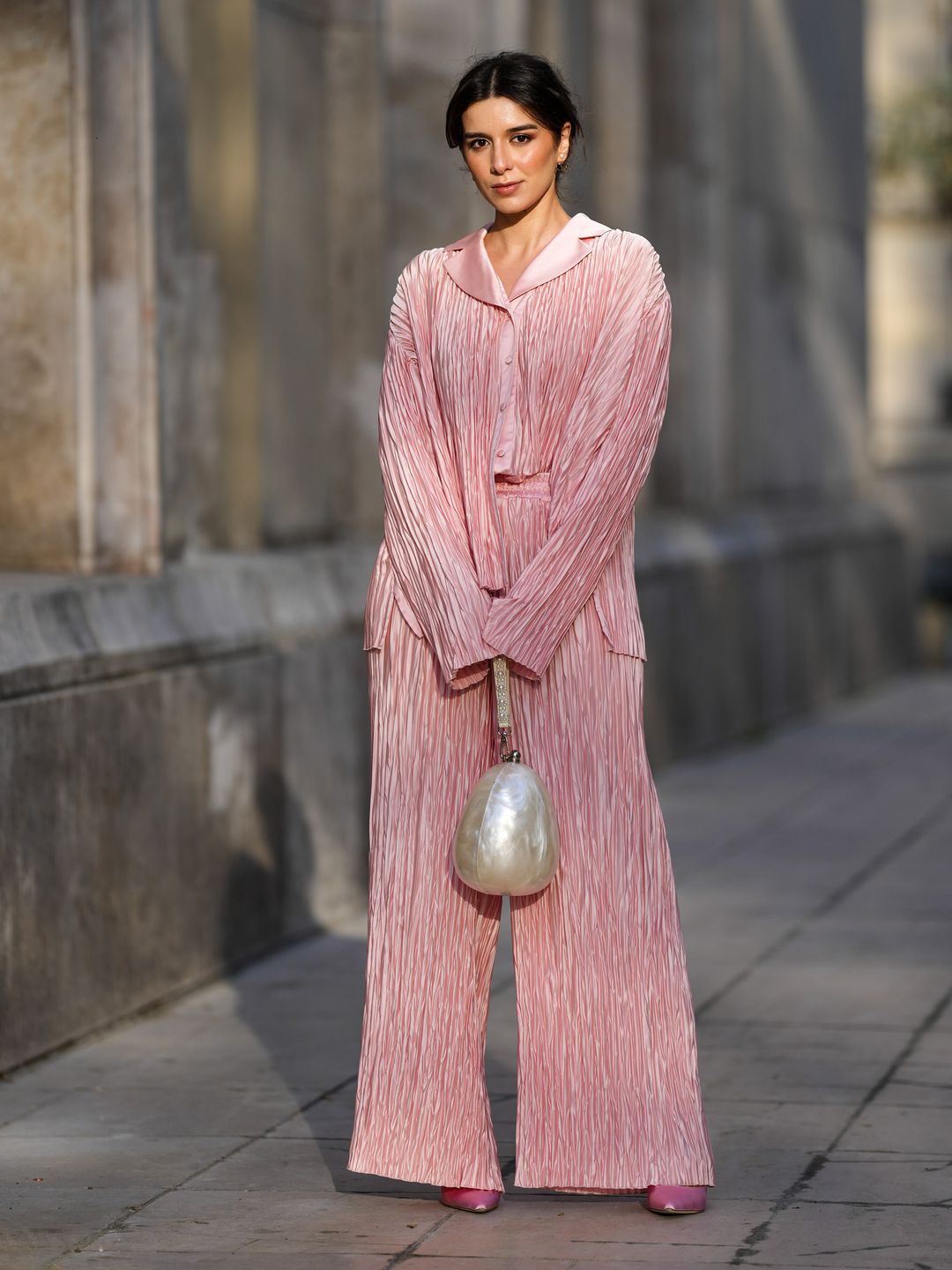 Katie Giorgadze wears Dior earrings, pleated pink pyjama trousers