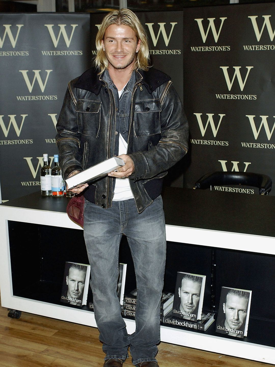 Footballer David Beckham holds his autobiography "My Side" at the Waterstone's Book store in Piccadilly on November 17, 2003 wearing jeans, a jean jacket and leather jacket overtop