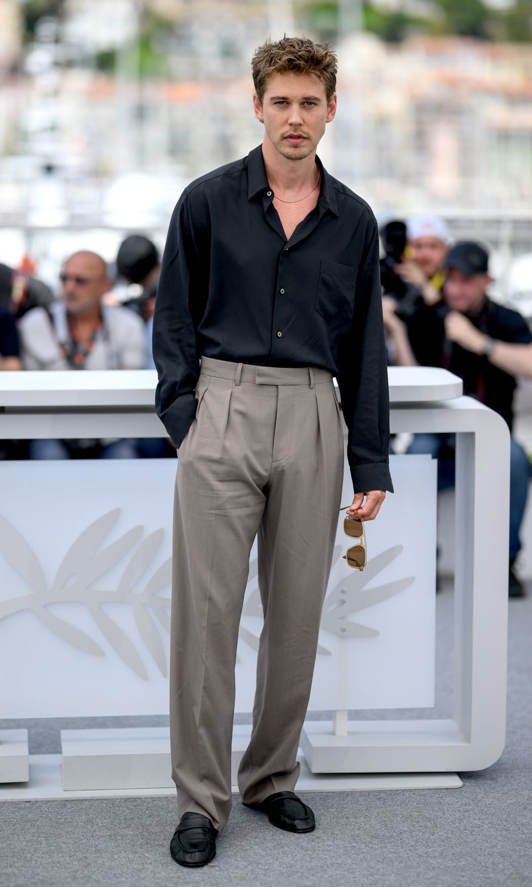 Austin Butler in a black shirt and grey trousers