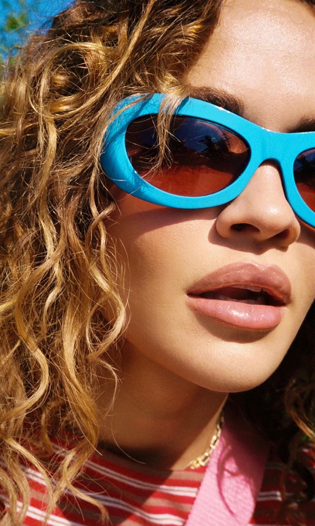 Rita Ora poses for a close-up photo in blue sunglasses