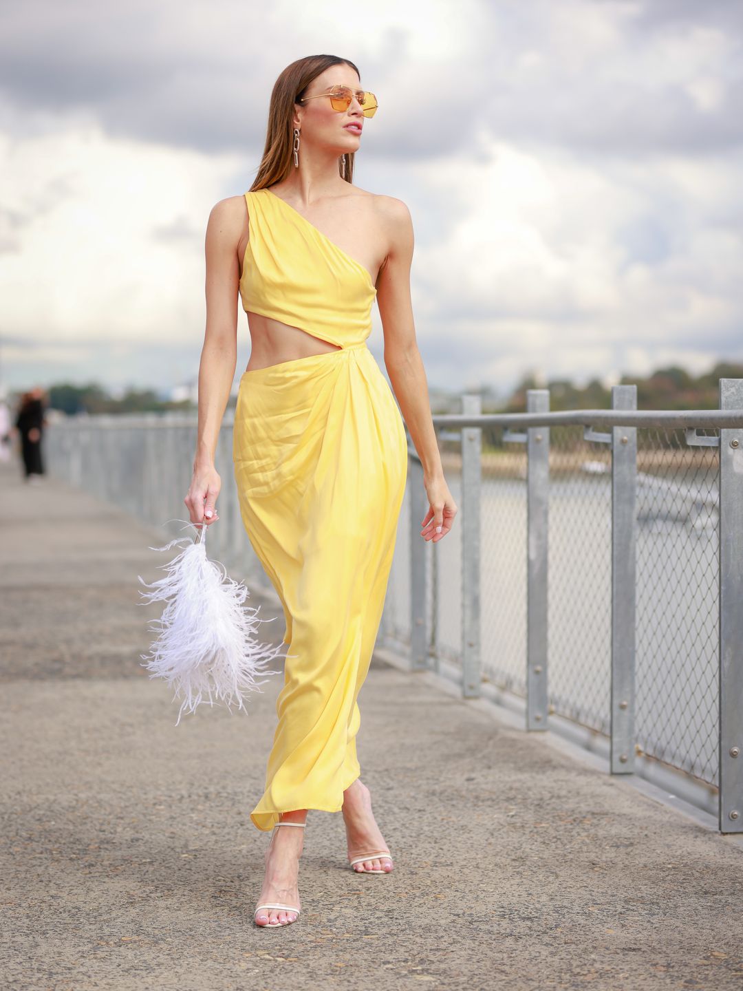 Erin Holland wears a yellow midi cut-out dress with a feather bag 