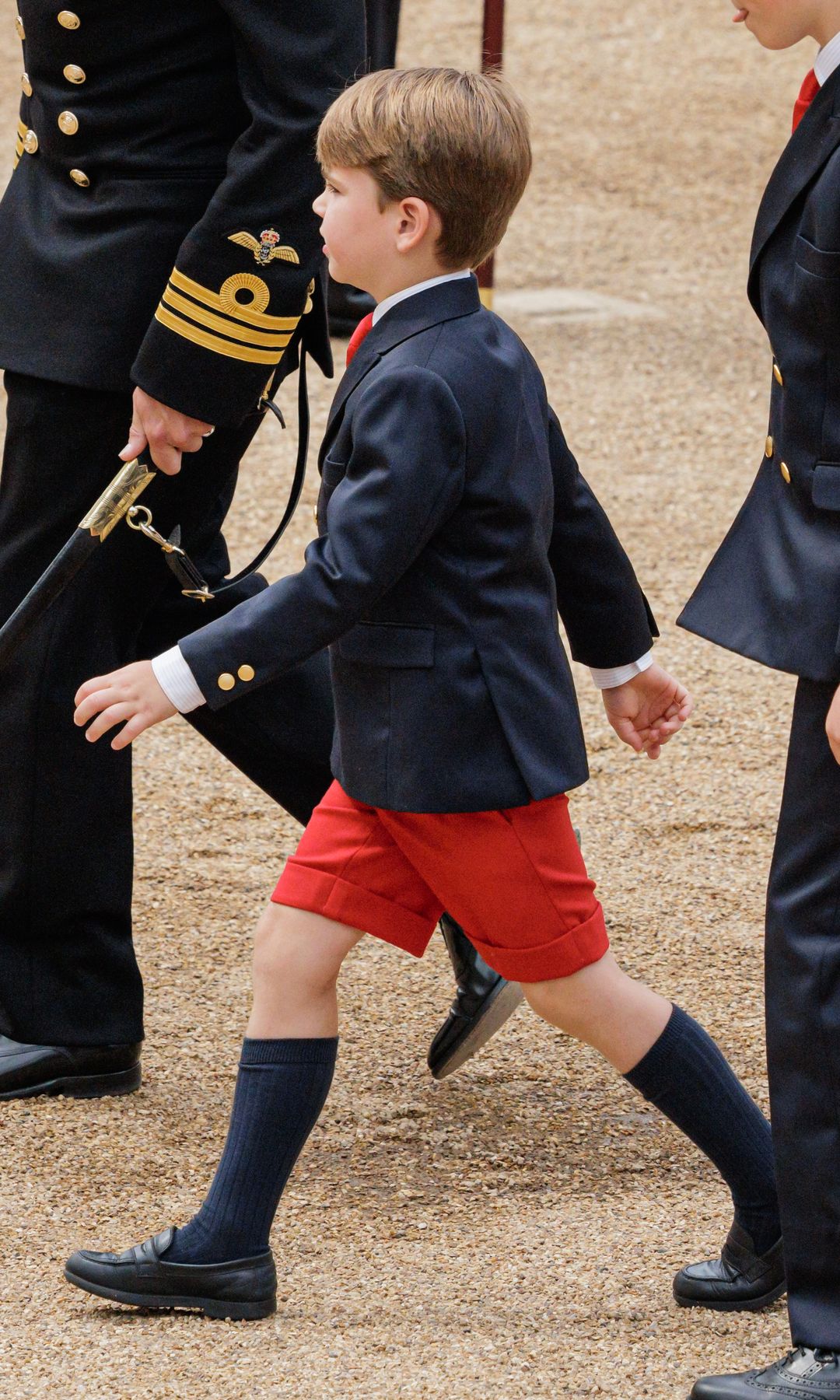 Prince Louis in red shorts walking with his siblings