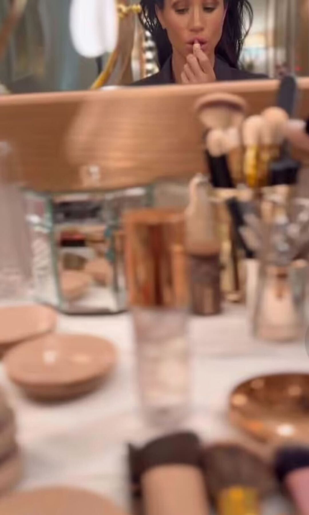 meghan markle applying lipstick in the mirror