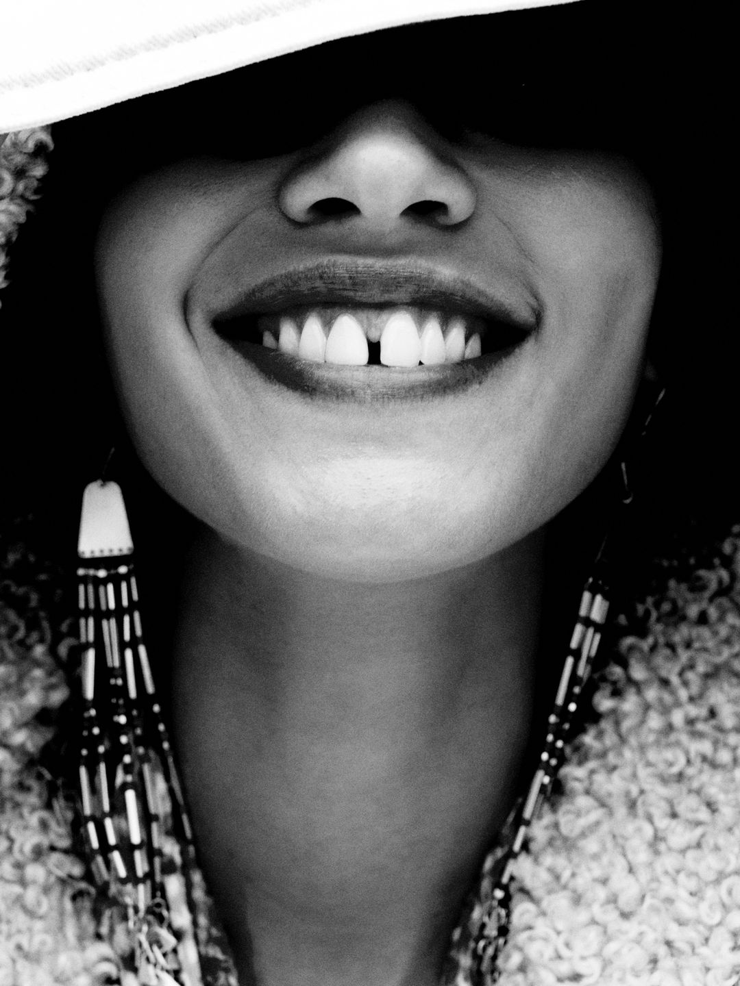 Woman smiling with eyes covered by hat 