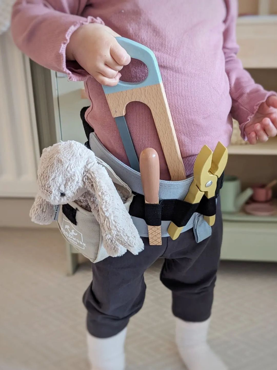 young girl wearing tool belt with wooden tools 