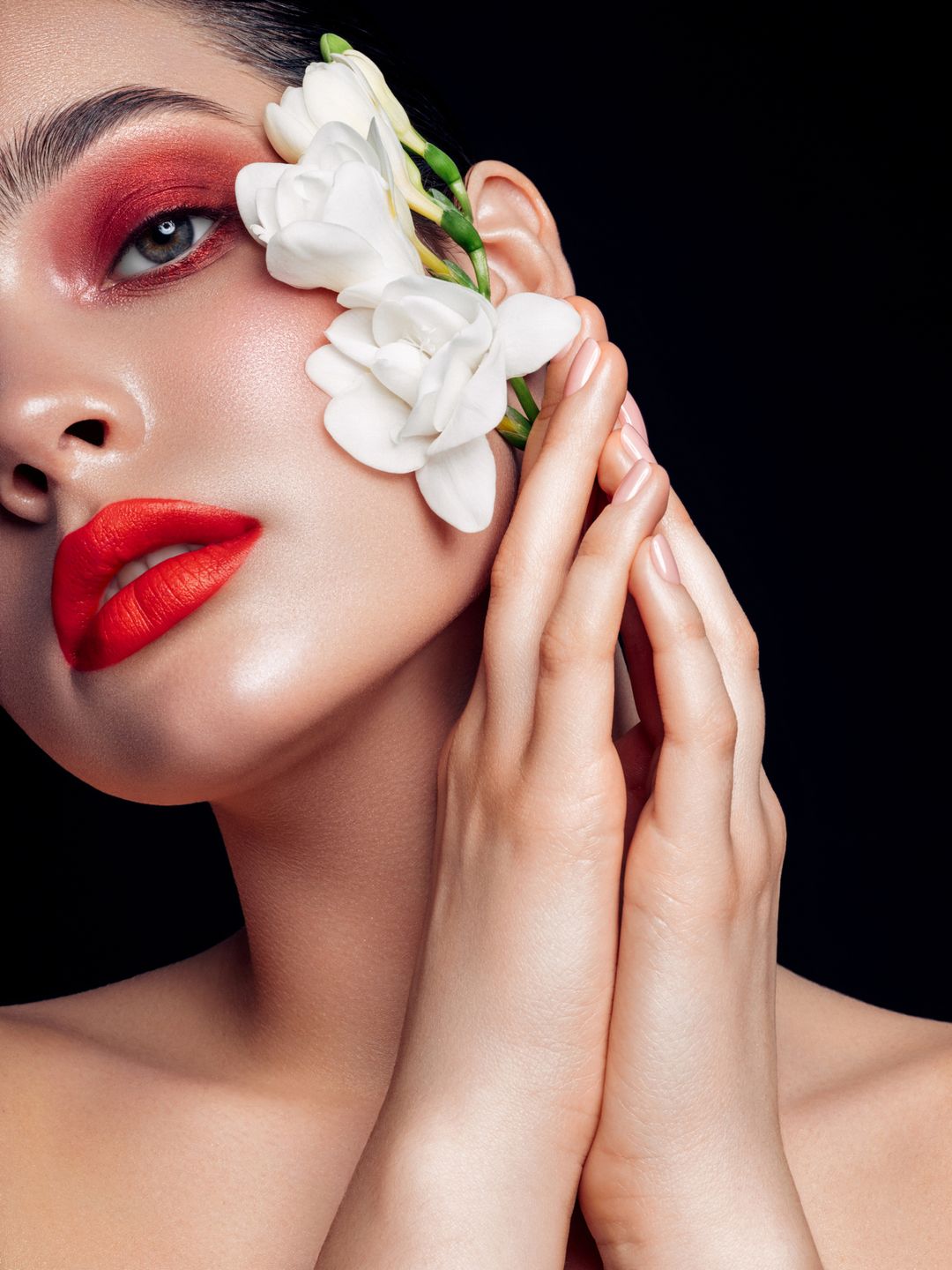 model wearing red lipstick with a nude manicure carrying white flowers
