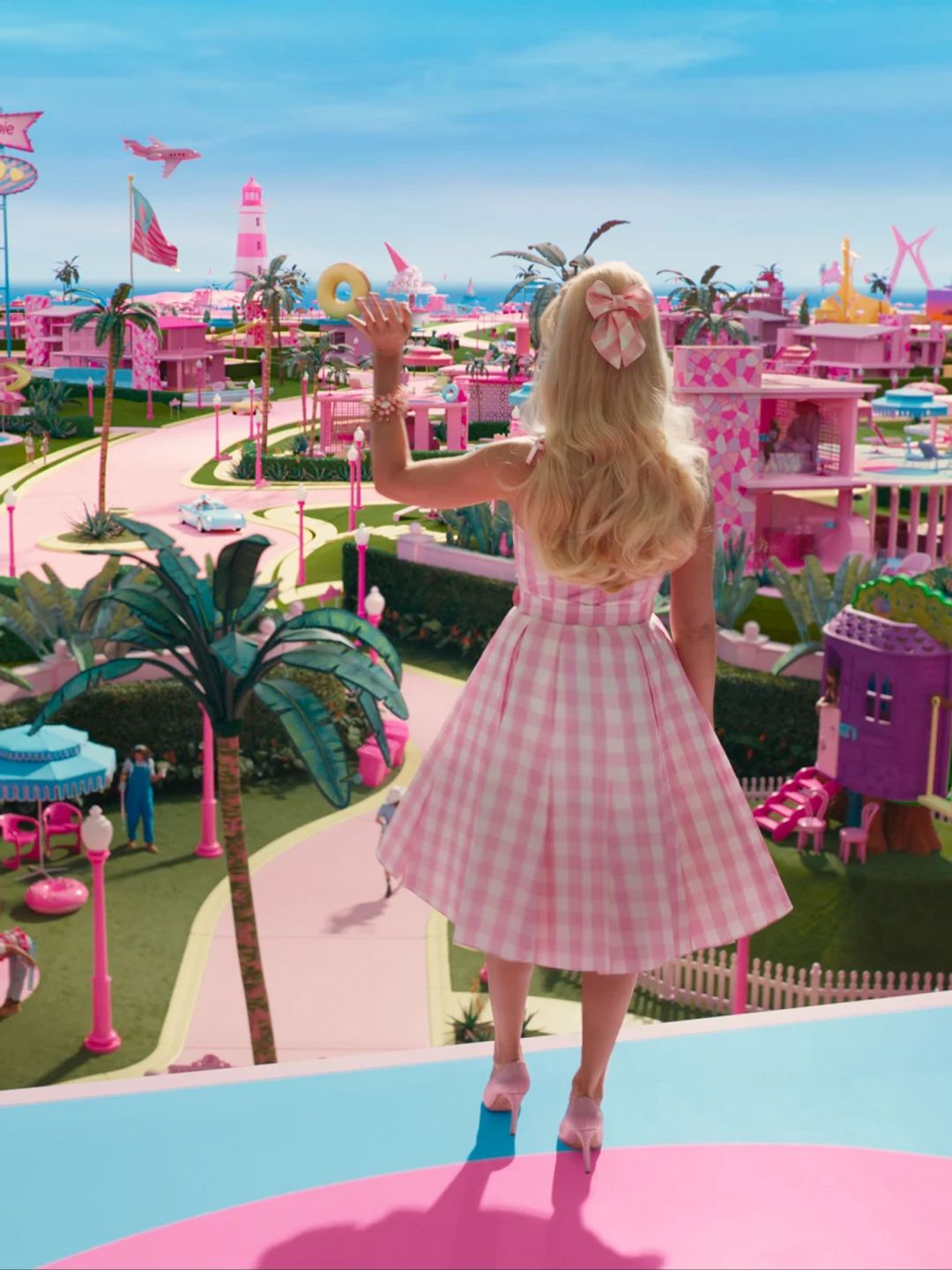 Margot Robbie dressed as Barbie with pink gingham outfit and hair bow