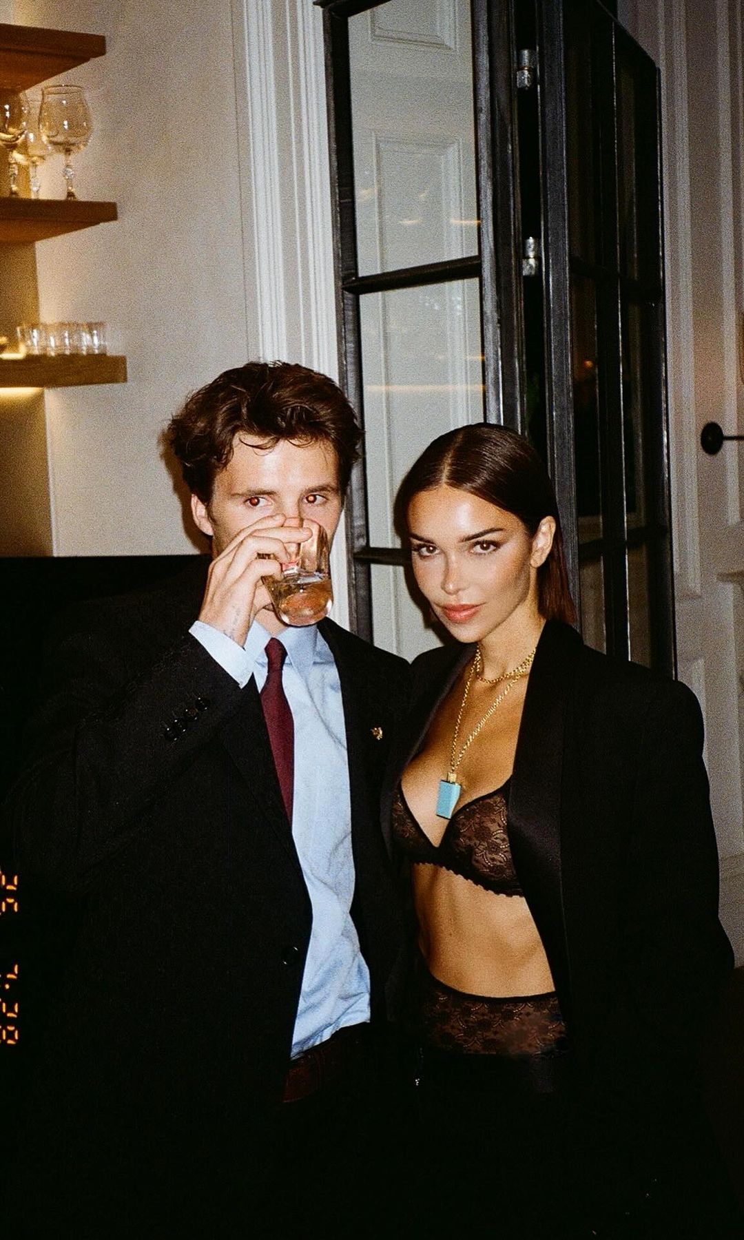 Jackie Apostel and Cruz Beckham pose for a picture in black suits 