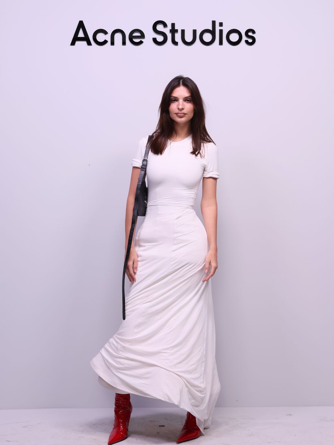 Emily Ratajkowski wore a simple yet widely elegant white structured dress and patent red boots to the Acne Studios show.