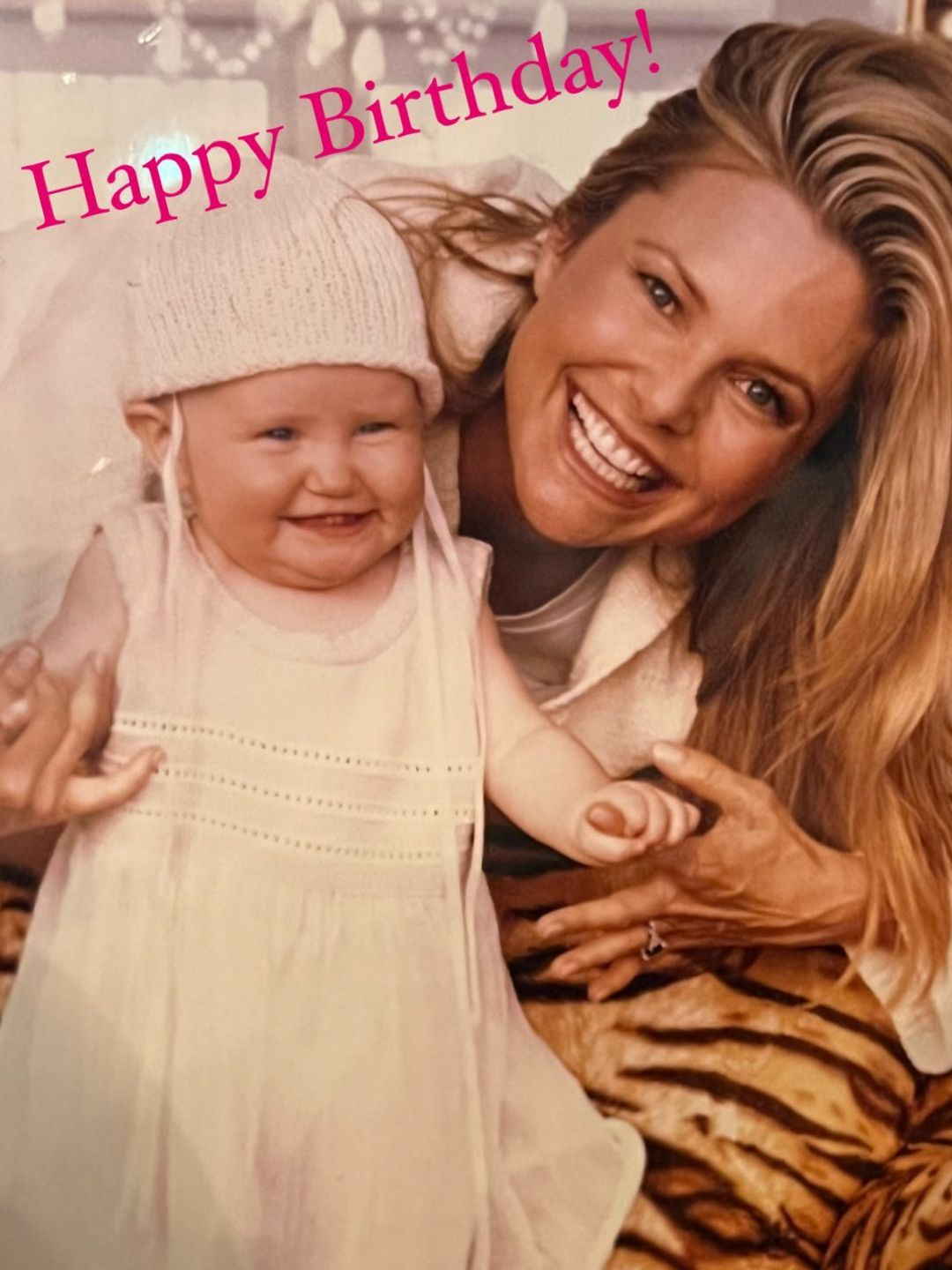 Christie smiling while helping a baby Sailor walk in an old photo