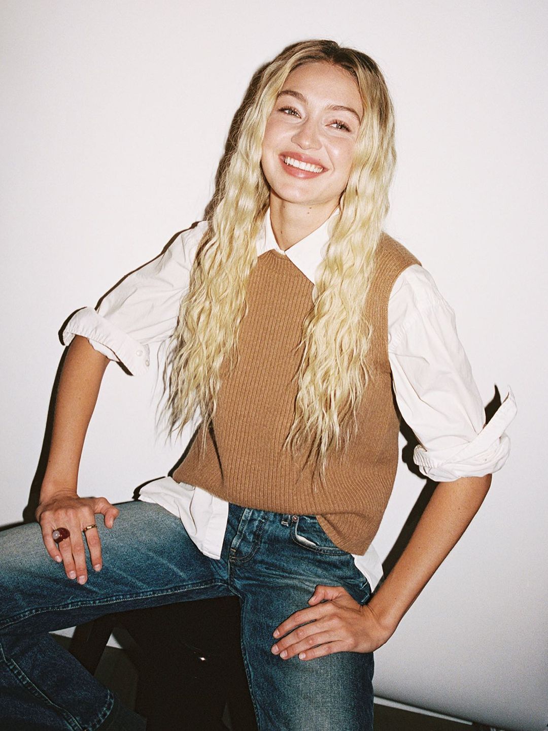 Gigi Hadid poses in a white shirt and sweater vest for her brand Guest In Residence