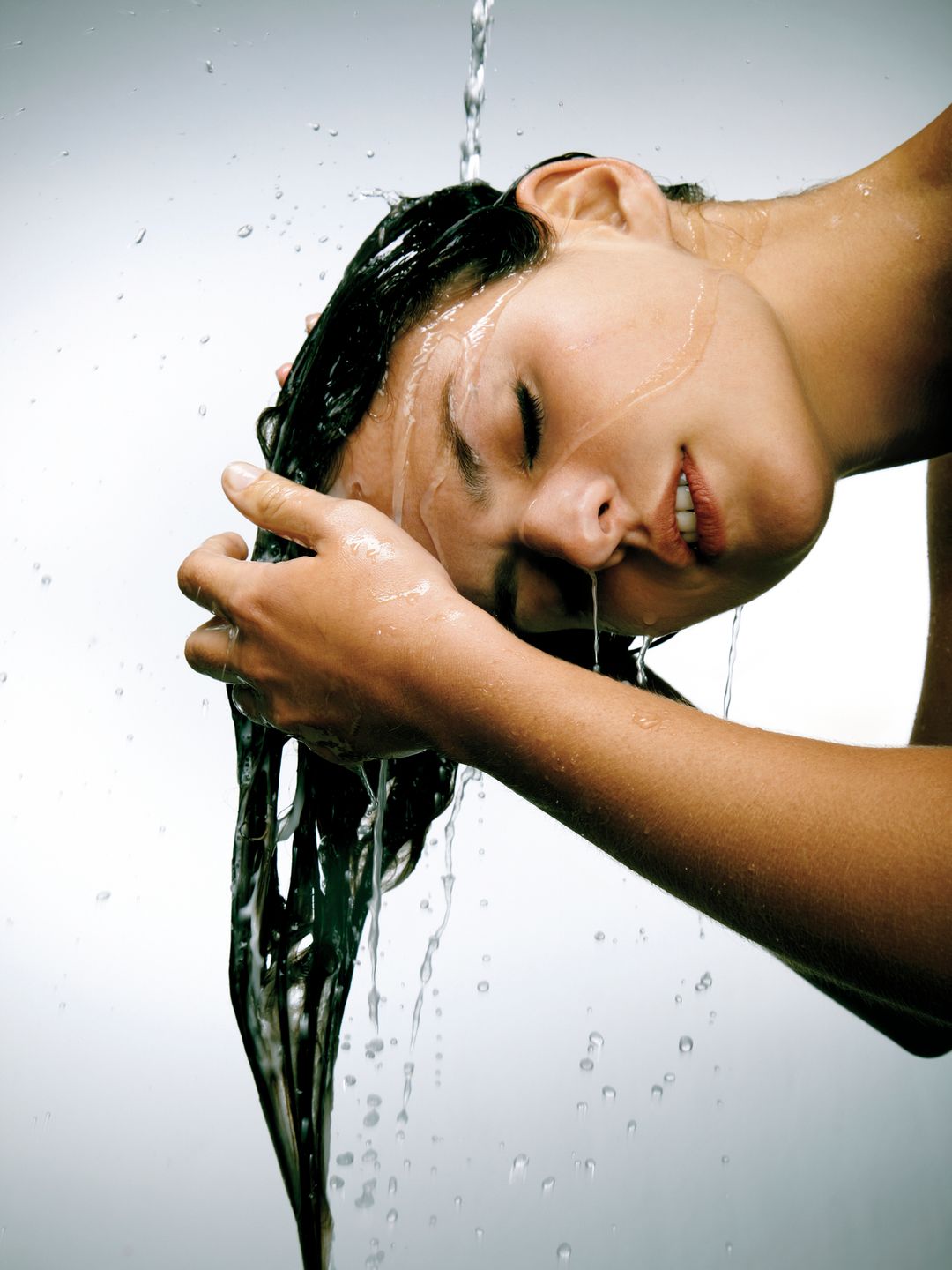 Young woman rinsing hair in water