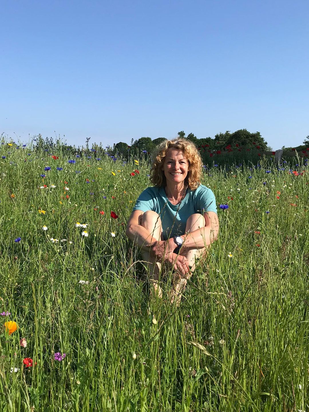 Kate Humble sitting in a field of flowers
