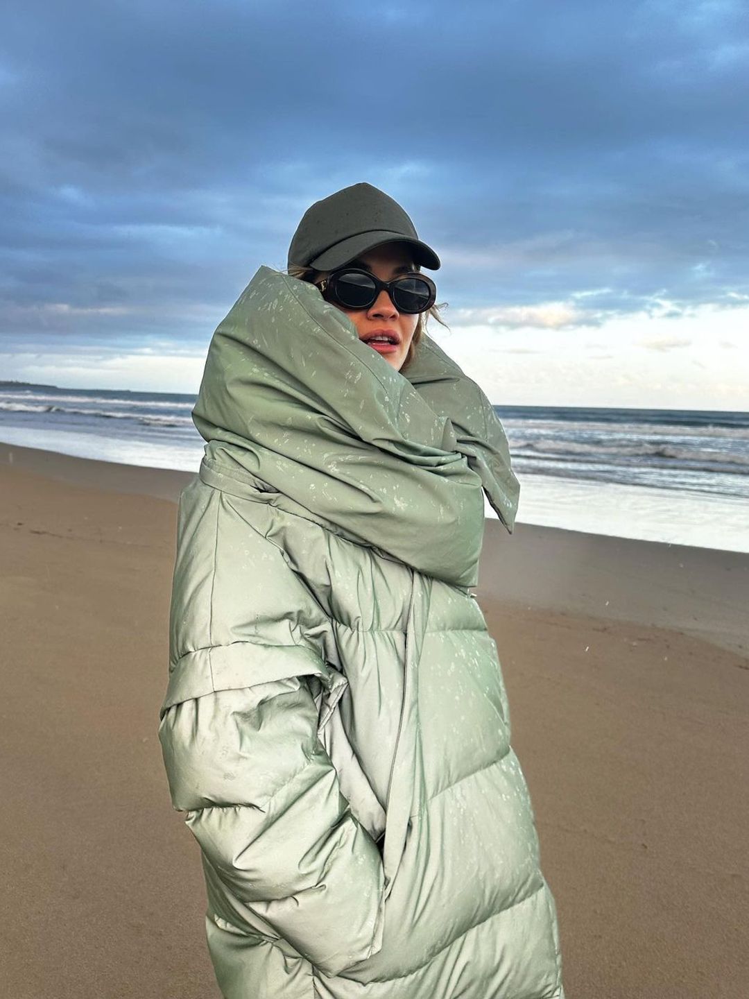 Rita snuggled up in her giant green puffer jacket for a winter beach walk 