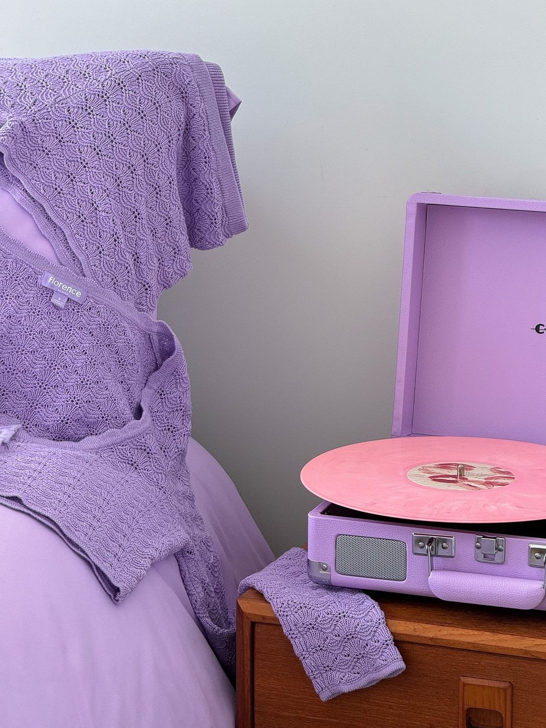 A picture of a purple loungewear set laying on a bed next to a record player