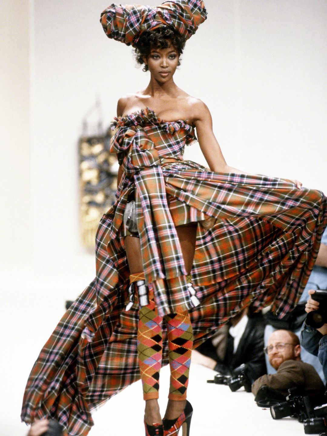 Naomi Campbell wearing a tartan strapless dress with matching platforms 
