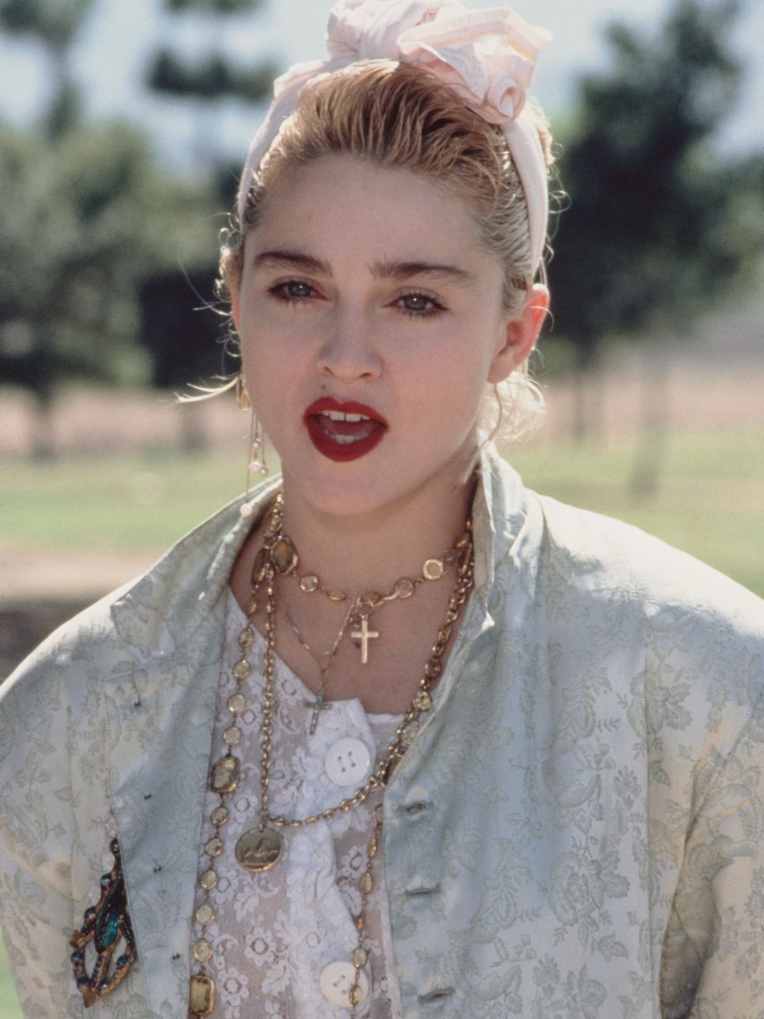 Madonna wearing a headband with red lips and layered necklaces 