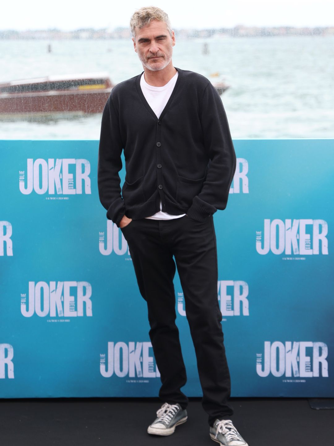 Joaquin Phoenix in a black jumper, white shirt and black trousers