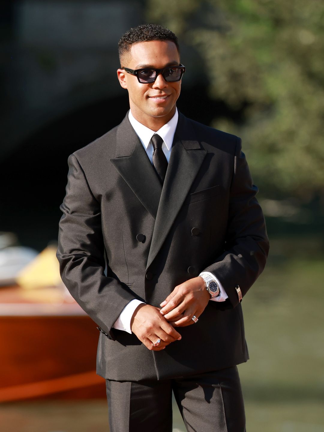 Lucien Laviscount in a black suit and sunglasses