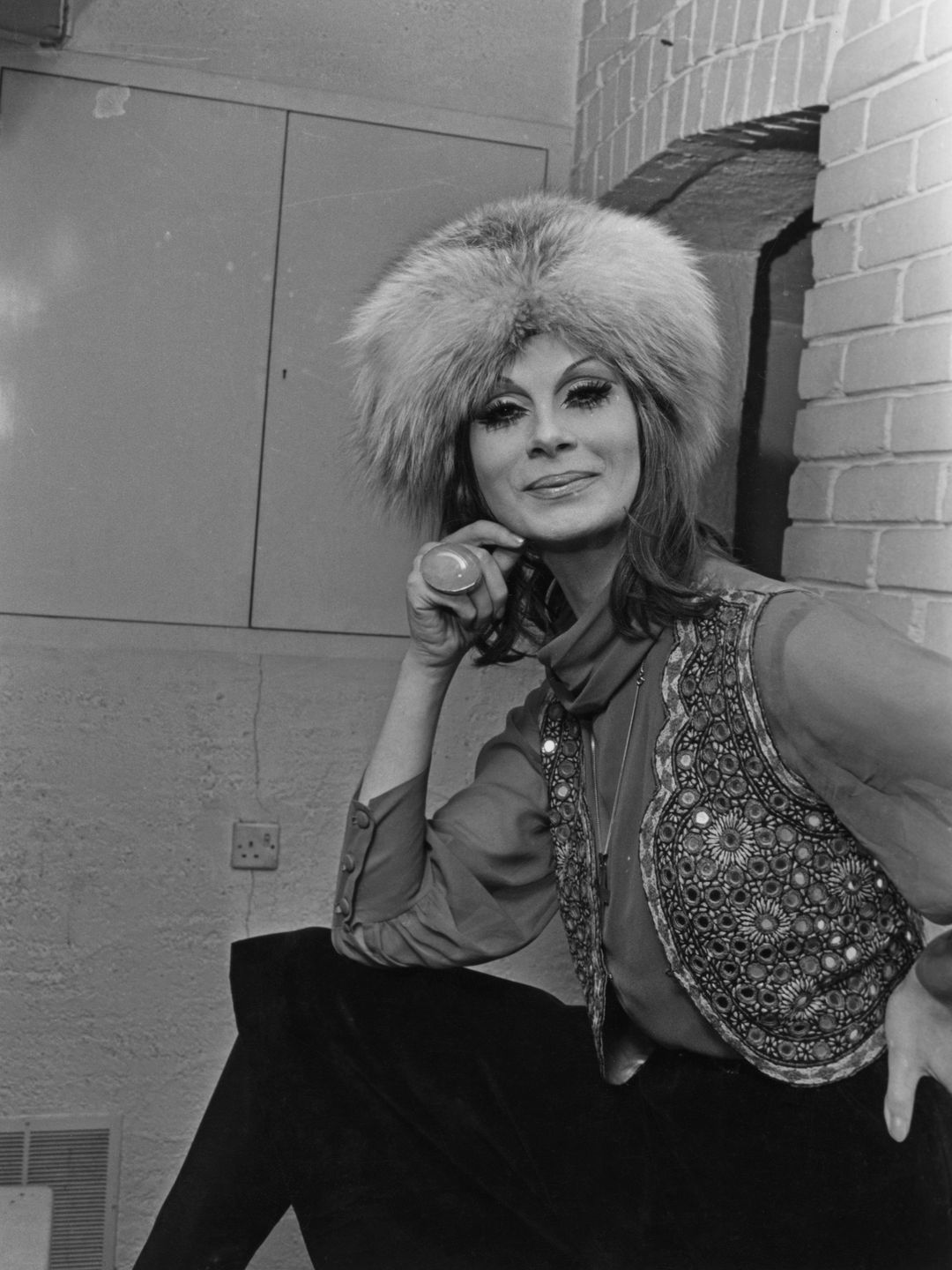 April Ashley wearing a fur hat and embellished waistcoat