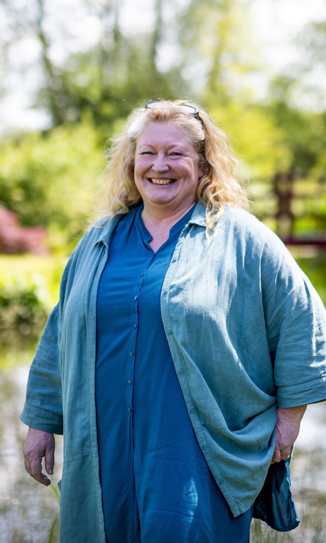 Charlie Dimmock in a blue outfit with a bridge behind her