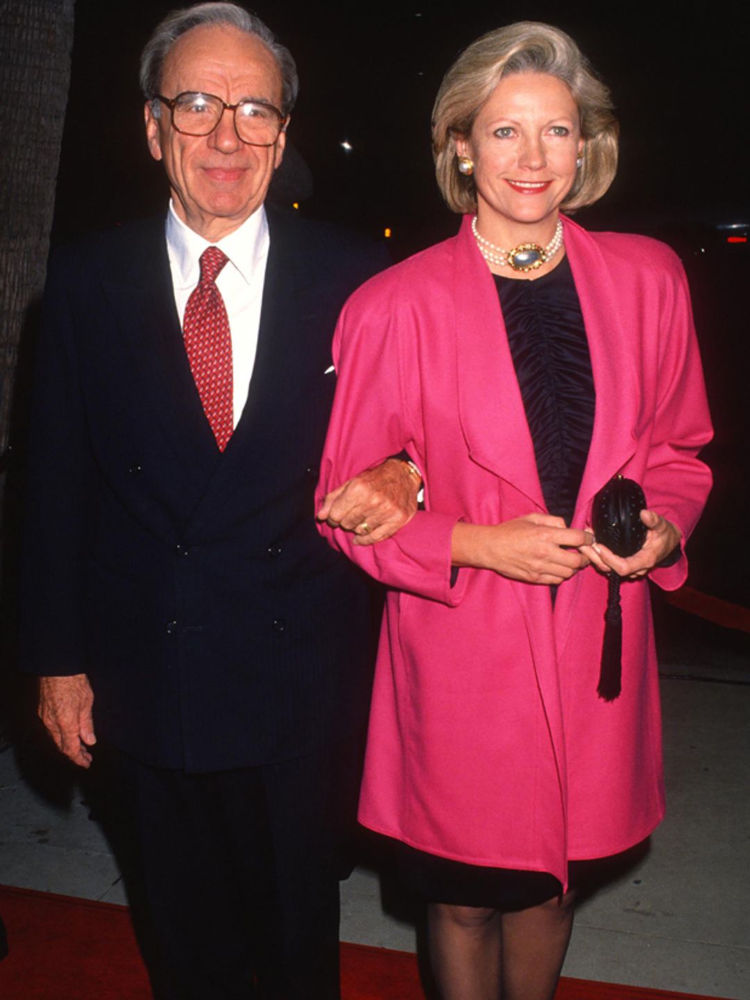 Rupert Murdoch in a suit linking arms with his ex wife Anna in a pink jacket